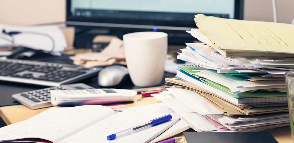 Dirty workplace desk with pile of paper