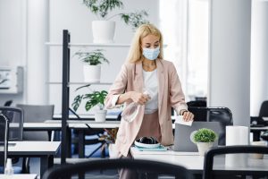 Employee wiping her desk with cleaning equipment to stay safe from COVID-19 virus