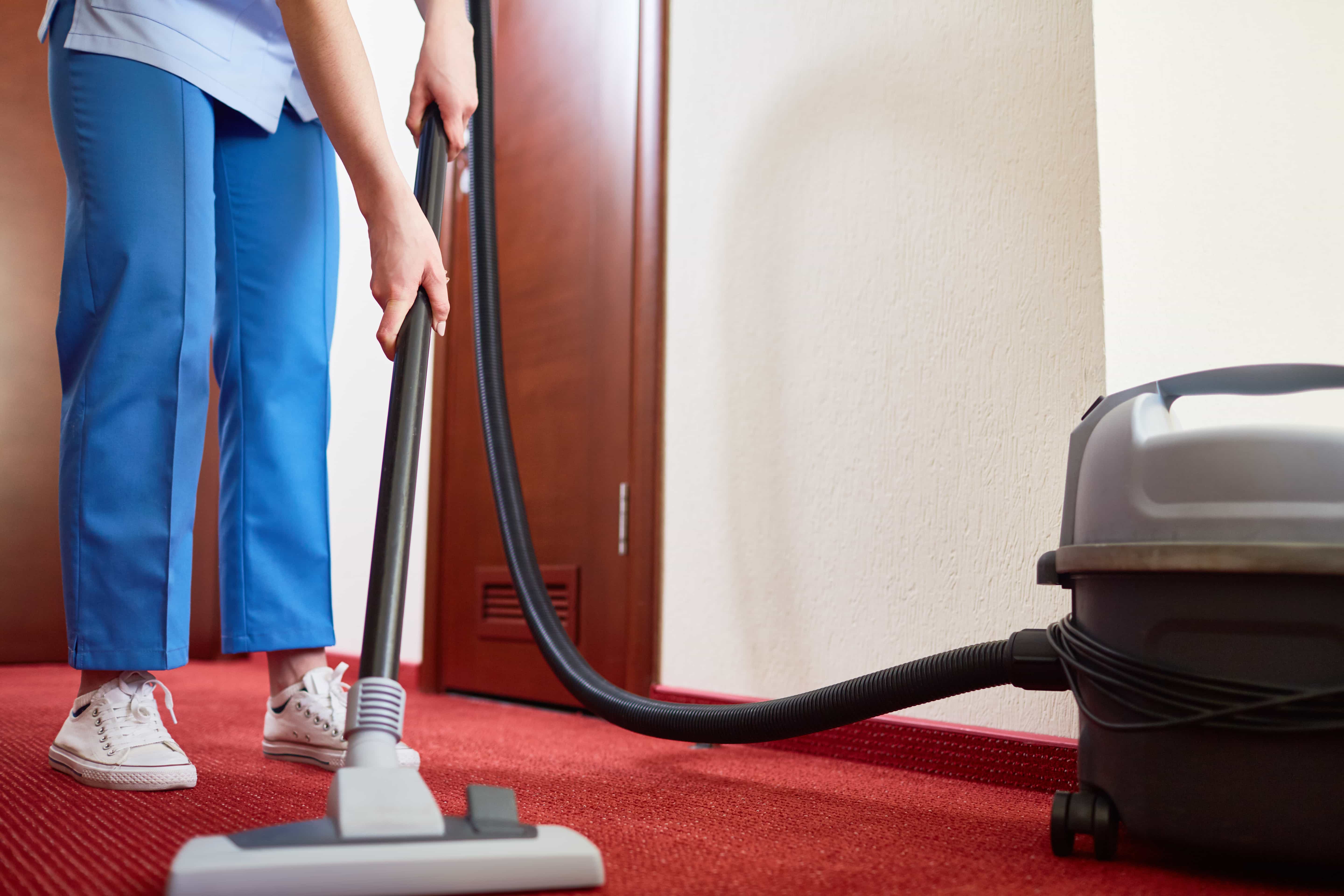 Commercial cleaner vacuuming carper in hotel room