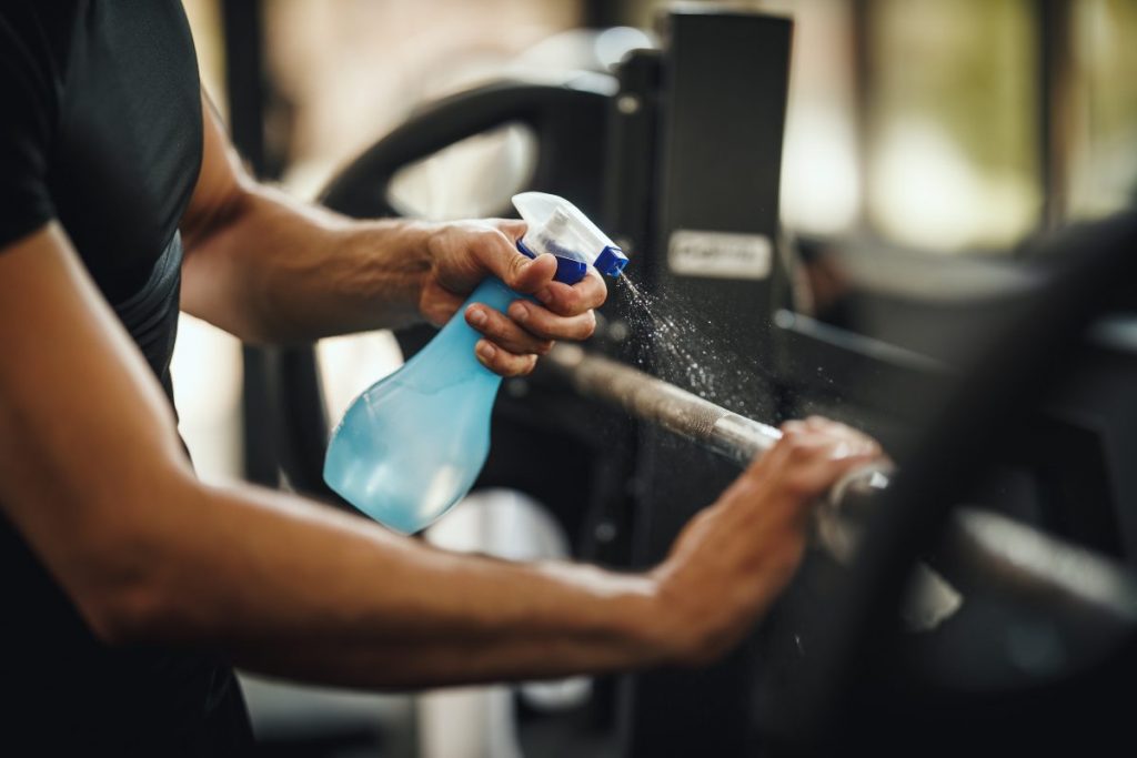 cleaning weights with disinfectant at a gym